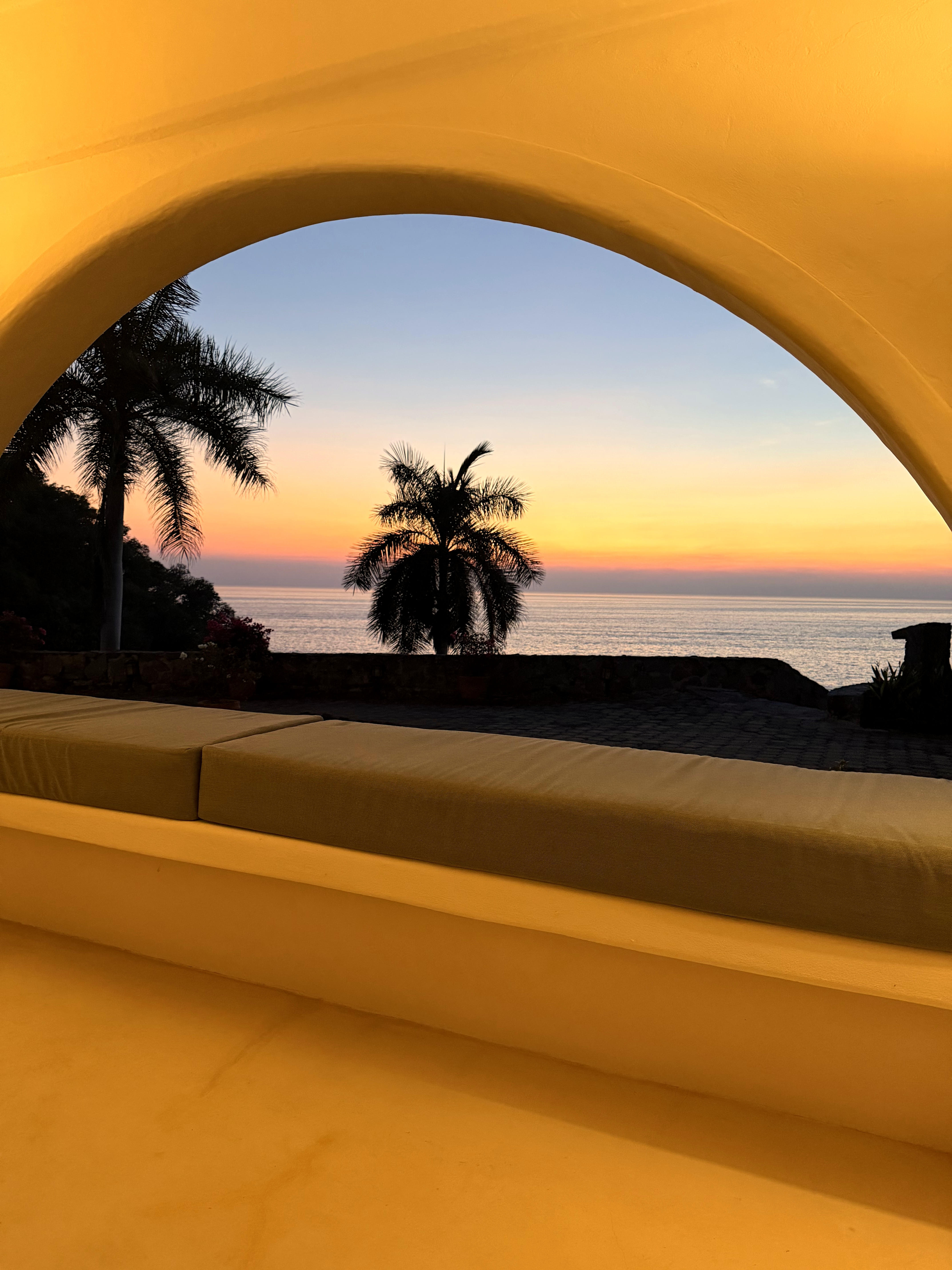 Arched daybed nook framing a Pacific sunset