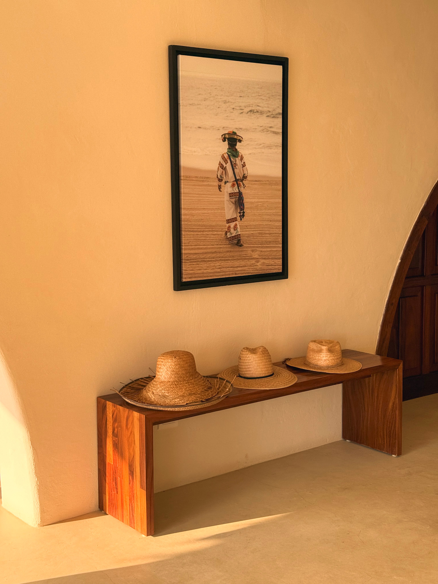 Entryway bench with woven sun hats and framed portrait