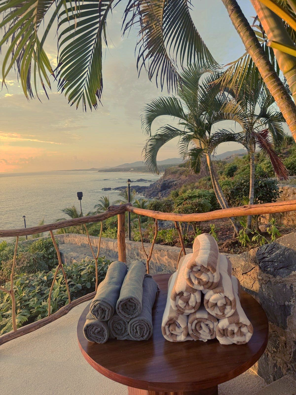 Rolled towels on a cliffside terrace table at sunset overlooking the Pacific